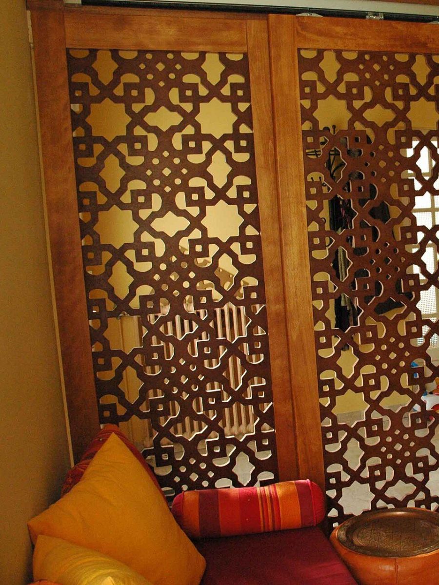 ركن مجلس بوسائد ملوّنة أمام فاصل مشربية خشبي يتسلّل منه الضوء