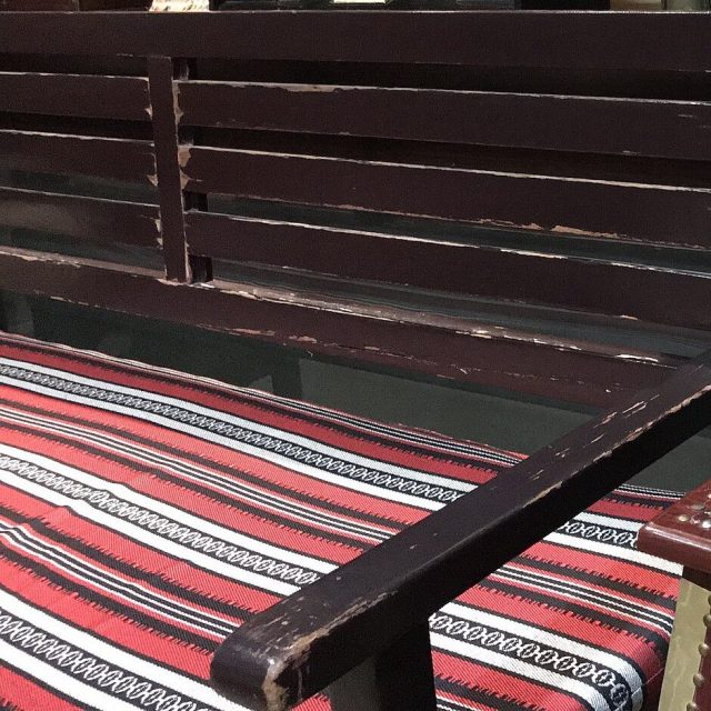 مقعد خشبي داكن بوسادة مخططة بالأحمر والأسود